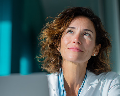 Médica reflexionando sobre su práctica profesional, representando los retos que enfrenta y cómo la educación médica online de DoctorIQ puede ayudarle